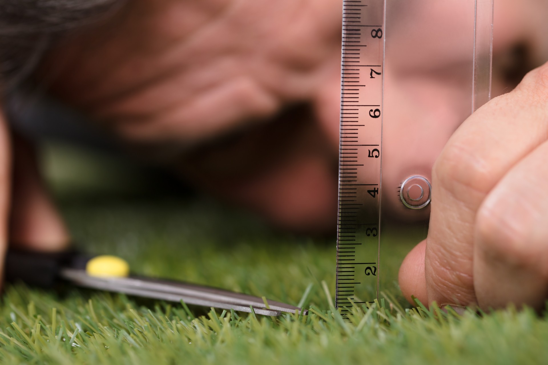 Man Using Measuring Scale While Cutting Grass